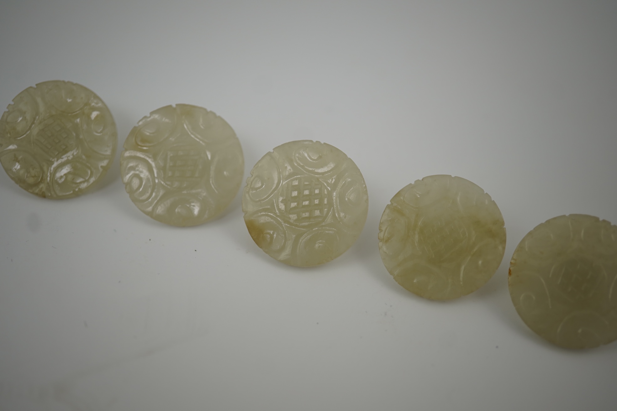 A set of five Chinese pale celadon jade robe buttons, 19th century